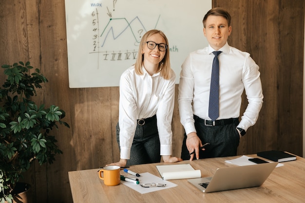 Smiling businesswoman and secretary are working with a laptop and documents at their desk in the office