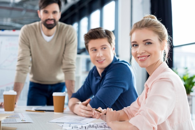 Smiling businesswoman sitting at table with colleagues on business meeting