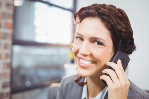 Smiling businesswoman talking on mobile phone in office