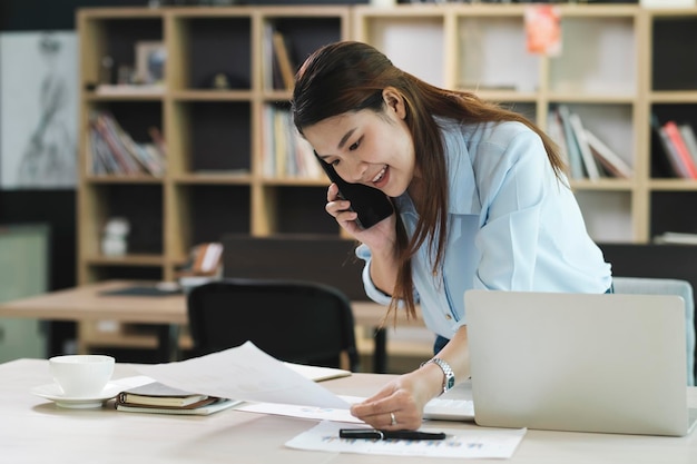 Photo smiling businesswoman talking on smartphone while waiting client in office