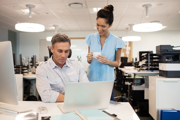 Smiling businesswoman talking with male colleague in office