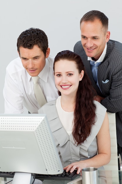 Smiling businesswoman and two businessmen using a computer