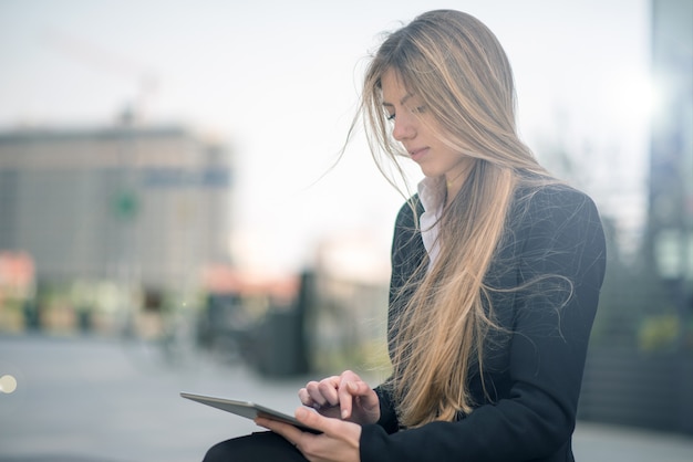 Улыбающаяся деловая женщина с помощью цифрового планшета на открытом воздухе