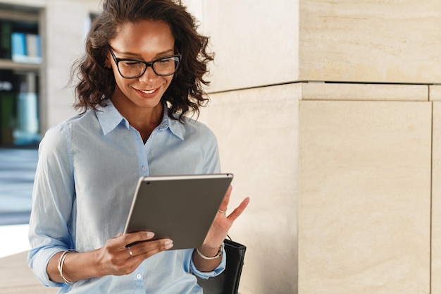 Photo smiling businesswoman using digital tablet while standing in office