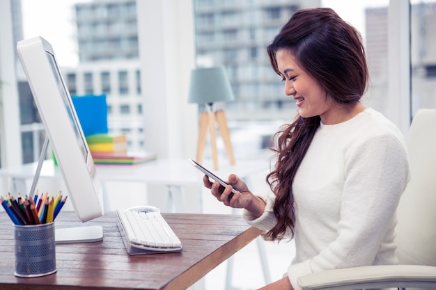 Smiling businesswoman using smartphone in office