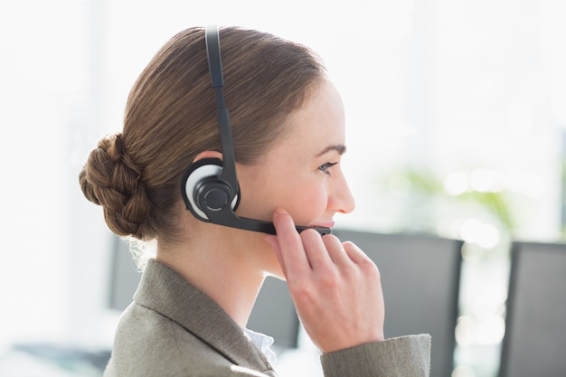 Smiling businesswoman with headset using computers