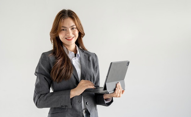 Улыбающаяся деловая женщина с ноутбуком, стоящая на белом фоне и смотрящая в камеру
