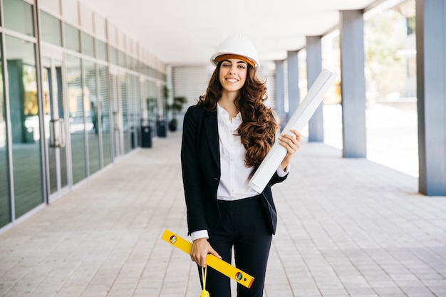 Smiling businesswoman with plan and level