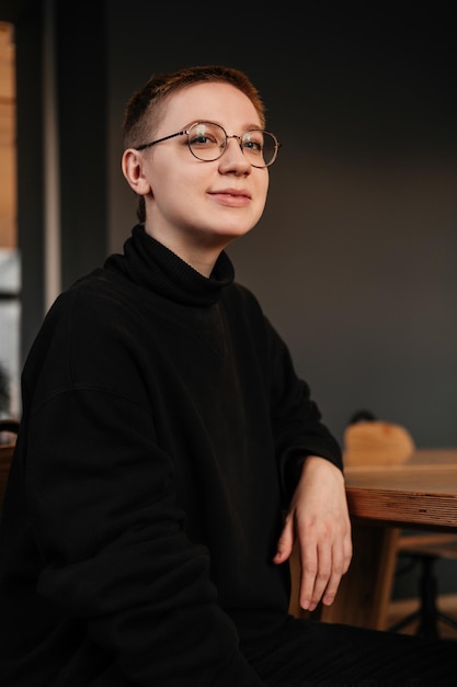 Smiling businesswoman with short hair in eyeglasses black sweater sitting at the table