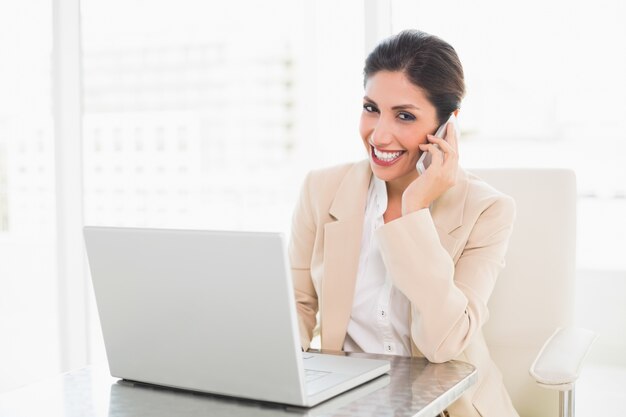 Smiling businesswoman working with a laptop on the phone