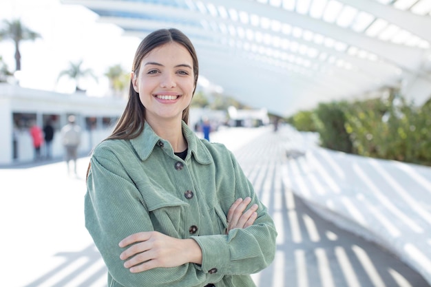 Smiling to camera with crossed arms and a happy confident satisfied expression lateral view