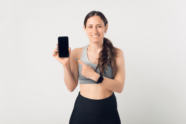 Sorridendo alla telecamera, la donna indica il telefono che tiene in mano.