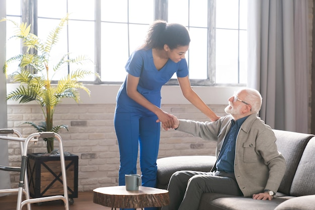 Smiling caring woman doctor talk consult satisfied elderly male patient give visit to retired