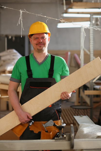 smiling carpenter holding wood