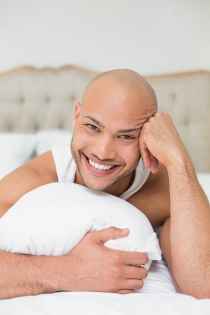 Smiling casual bald young man lying in bed