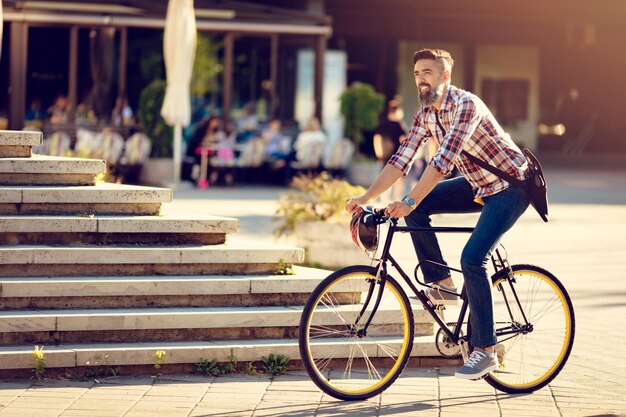 自転車で仕事に行く笑顔のカジュアルなビジネスマン。