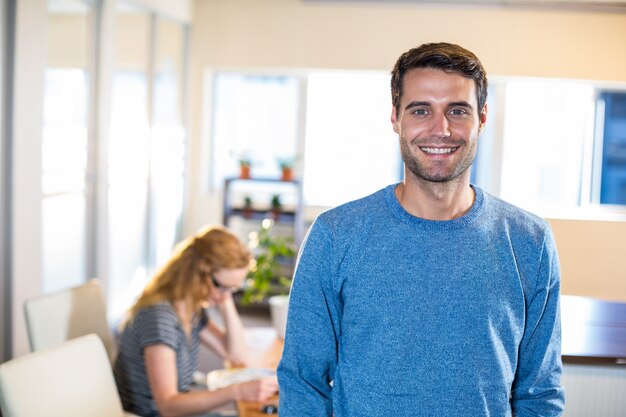 Smiling casual businessman posing with his partner behind 