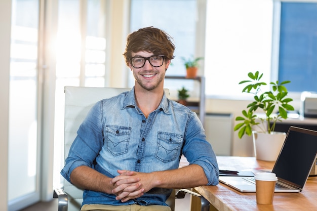 Smiling casual businessman sitting at desk