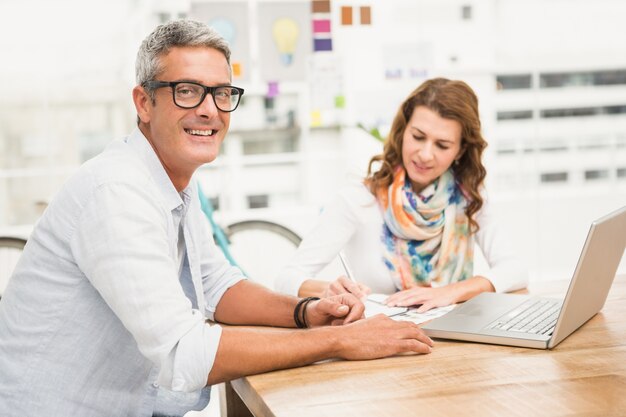 Smiling casual designer in front of his working colleague