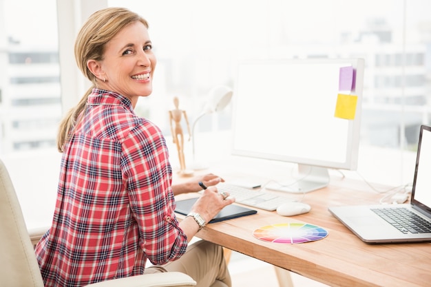 Smiling casual designer using computer and digitizer