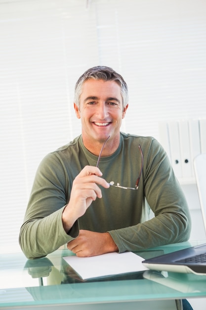 Smiling casual man holding his glasses