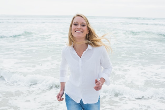 Smiling casual woman running at beach