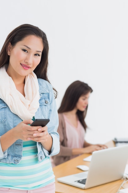 Smiling casual woman text messaging in office