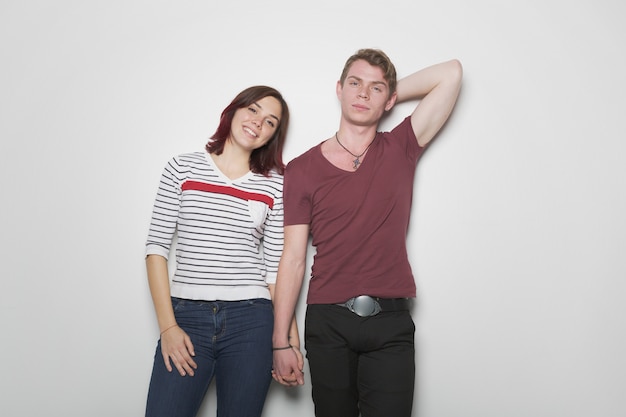 Smiling casual young couple posing on light wall