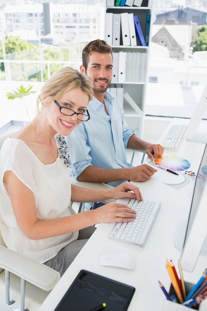 Smiling casual young couple working on computers