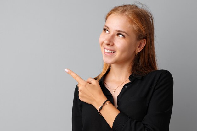 Giovane donna casuale sorridente che indica dito allo spazio della copia