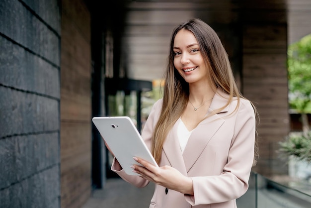 Smiling caucasian businesswoman standing and holding a tablet