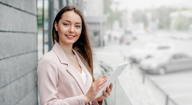 Smiling caucasian businesswoman standing and holding a tablet