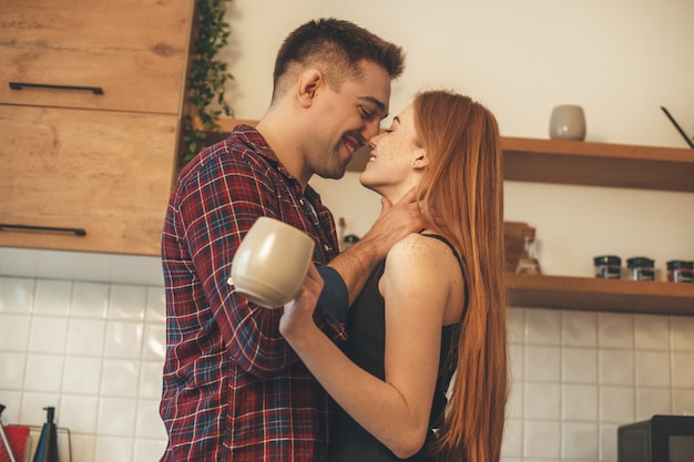 Smiling caucasian couple embracing and kissing each other in the kitchen