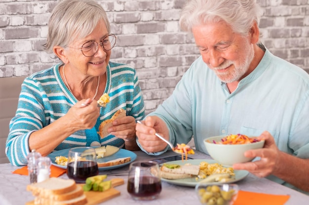 Photo smiling caucasian senior couple sitting at table having brunch together at home