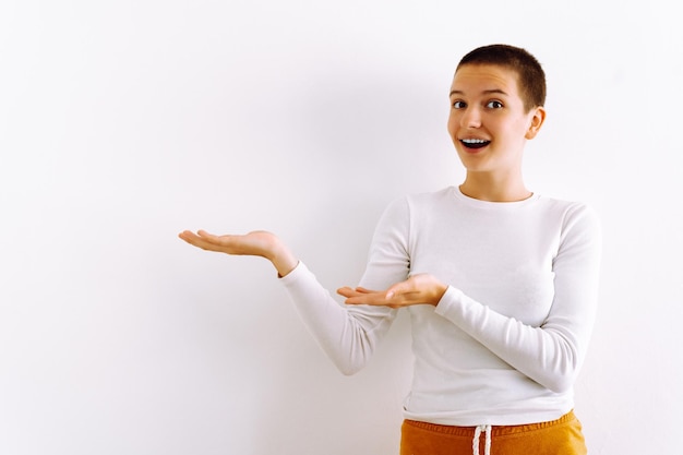 Smiling caucasian teenager girl with short haircut promotes new product