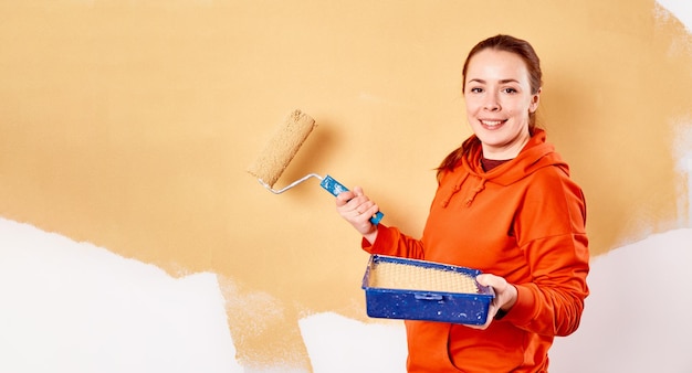 Улыбающаяся кавказская женщина рисует внутреннюю стену дома. Ремонт квартиры, ремонт и косметический ремонт. Концепция копирования пространства.