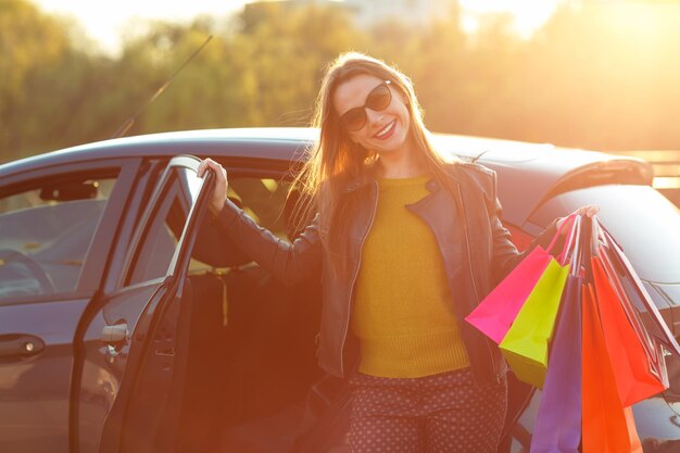 Smiling caucasian woman putting her shopping bags into the car shopping concept