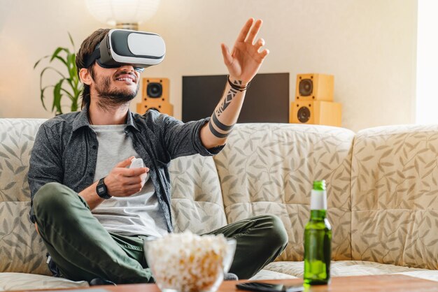 Smiling caucasian young man wearing virtual reality goggles at home