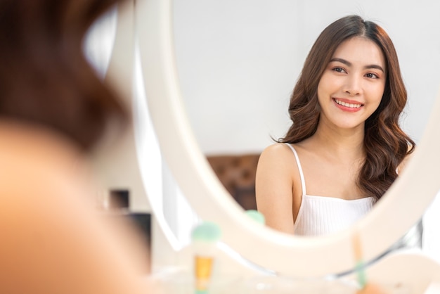 Smiling of cheerful beautiful pretty asian woman beauty clean fresh healthy white skin posing in white clothes.Girl felling relaxing and enjoy time look at mirror in home