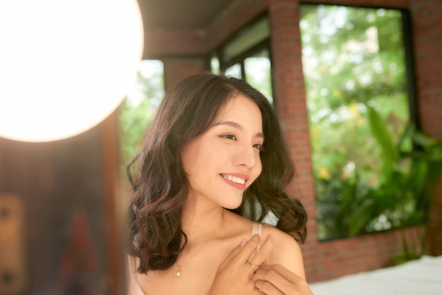 Улыбка веселой красивой симпатичной азиатской женщины, красота чистой свежей здоровой белой кожи, позирующей в белой одежде