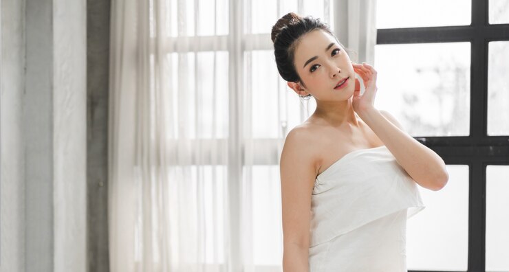 白い服でポーズをとって陽気な美しいかなりアジアの女性のきれいな新鮮な健康的な白い肌の笑顔
