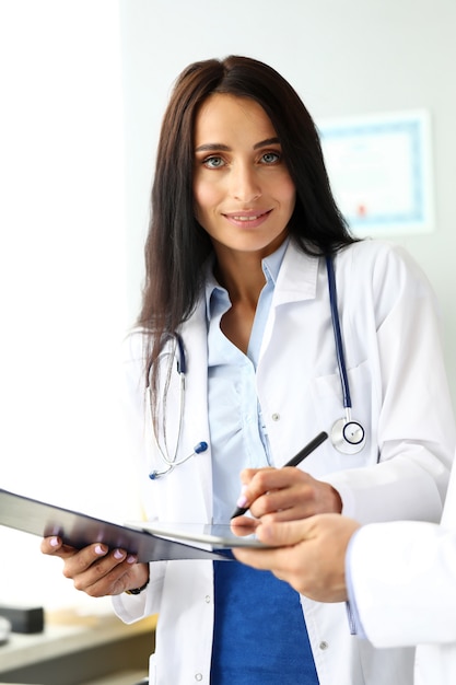 Smiling cheerful female GP making electronic notes