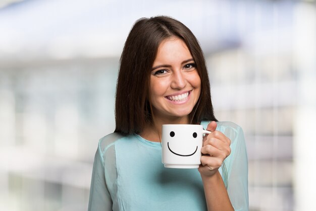 Smiling and cheerful woman holding a smiling cup