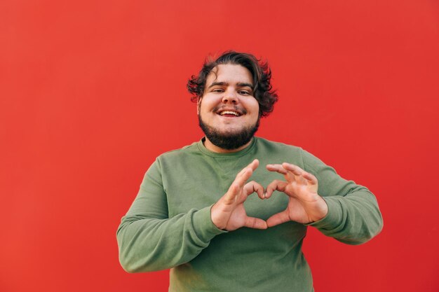 Smiling cheerful young obese hispanic man is expressing a love sigh gesture