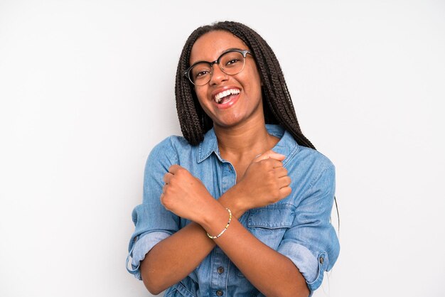 Photo smiling cheerfully and celebrating with fists clenched and arms crossed feeling happy and positive