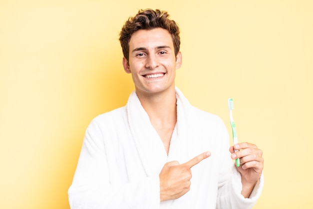 Smiling cheerfully, feeling happy and pointing to the side and upwards, showing object in copy space. tooth brush concept