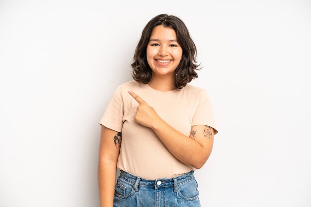 Smiling cheerfully feeling happy and pointing to the side and upwards showing object in copy space