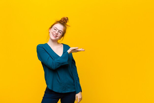 Sorridendo allegramente, sentendosi felice e mostrando un concetto nello spazio della copia con il palmo della mano