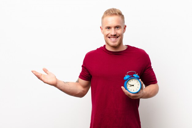 Foto sorridendo allegramente, sentendosi felice e mostrando un concetto nello spazio della copia con il palmo della mano