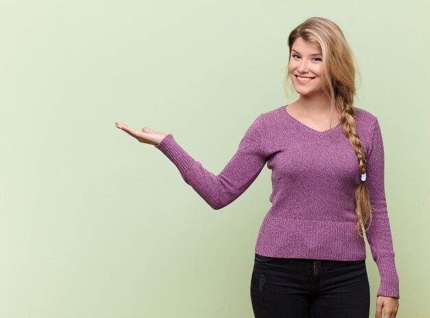 Foto sorridendo allegramente, sentendosi felice e mostrando un concetto nello spazio della copia con il palmo della mano